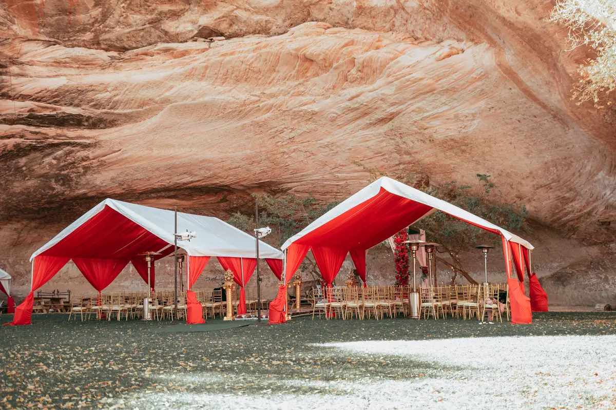 Red pavilions raised beneath a desert cliff