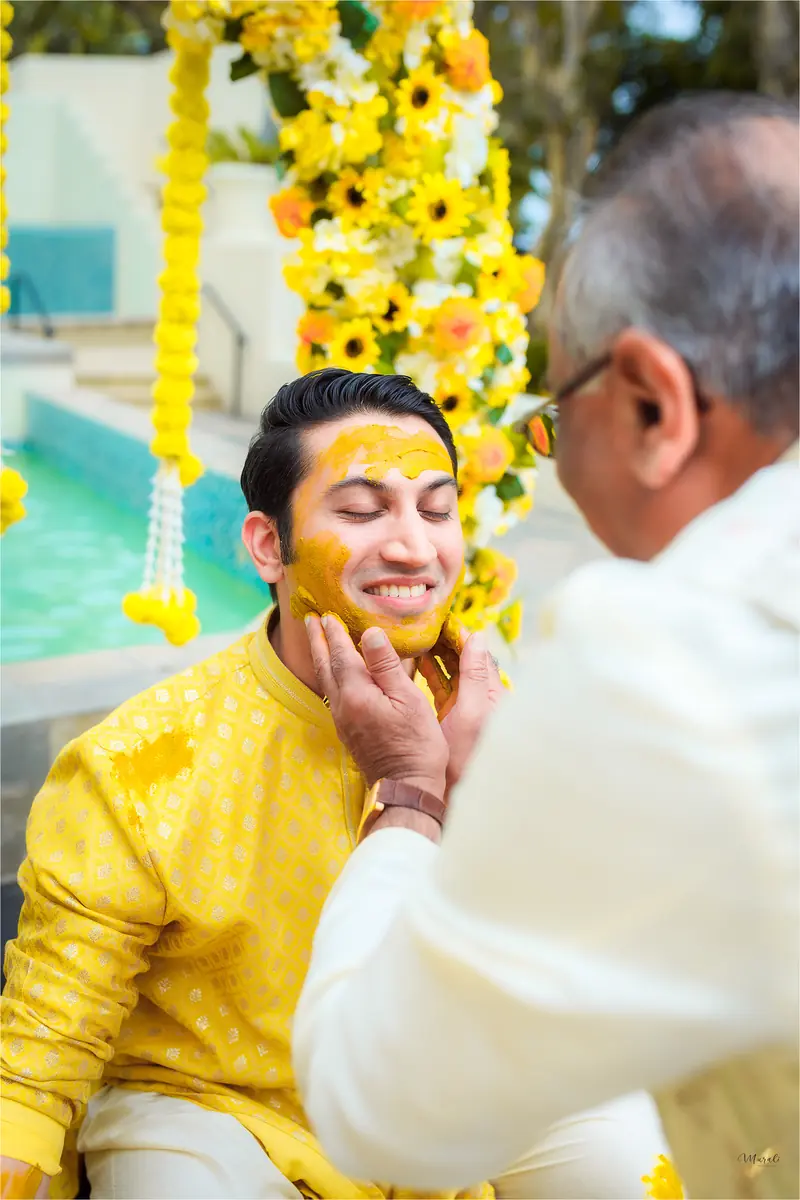 An elder lovingly applies turmeric to the groom at the haldi