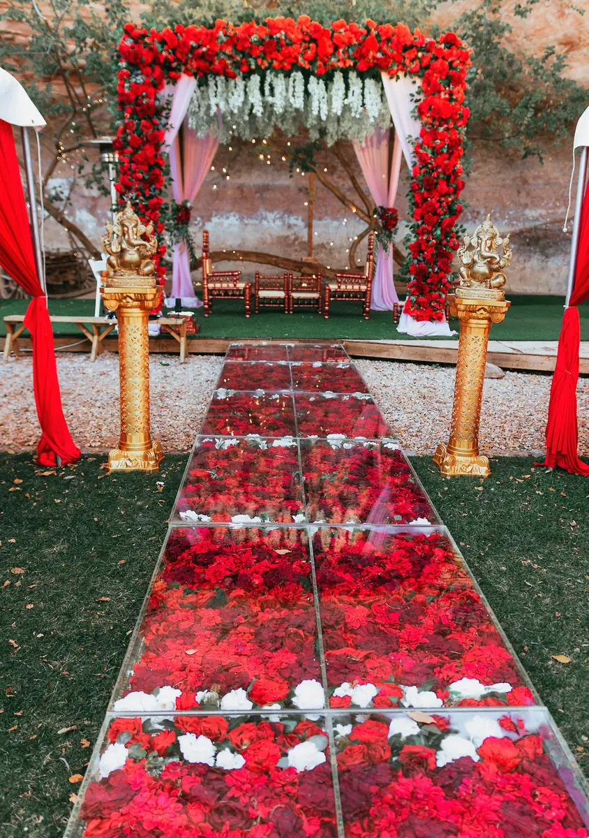 A rose-petal aisle leads to the mandap