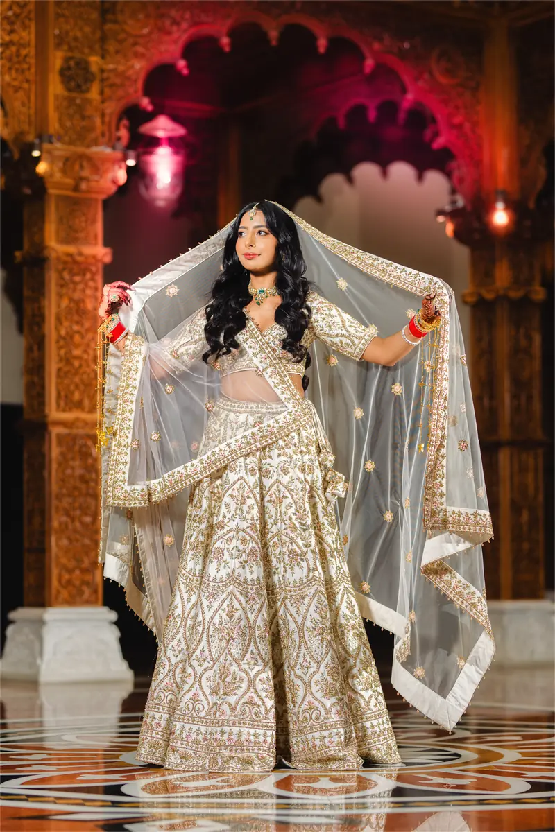 A bride turns, her veil open, in the carved mandir