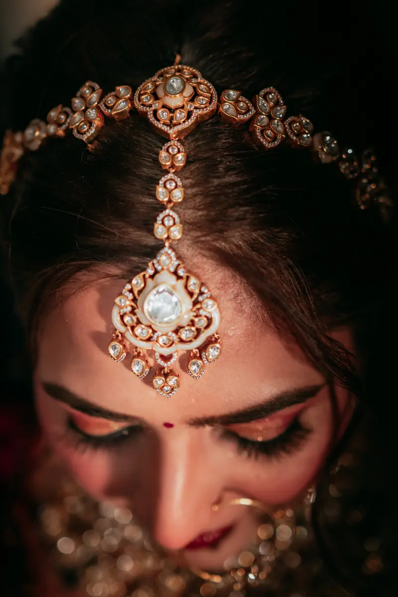 The maang tikka, eyes lowered